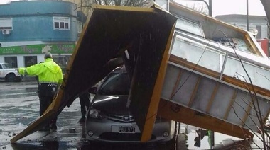 Por el fuerte temporal, un puesto de diarios terminó arriba de un auto